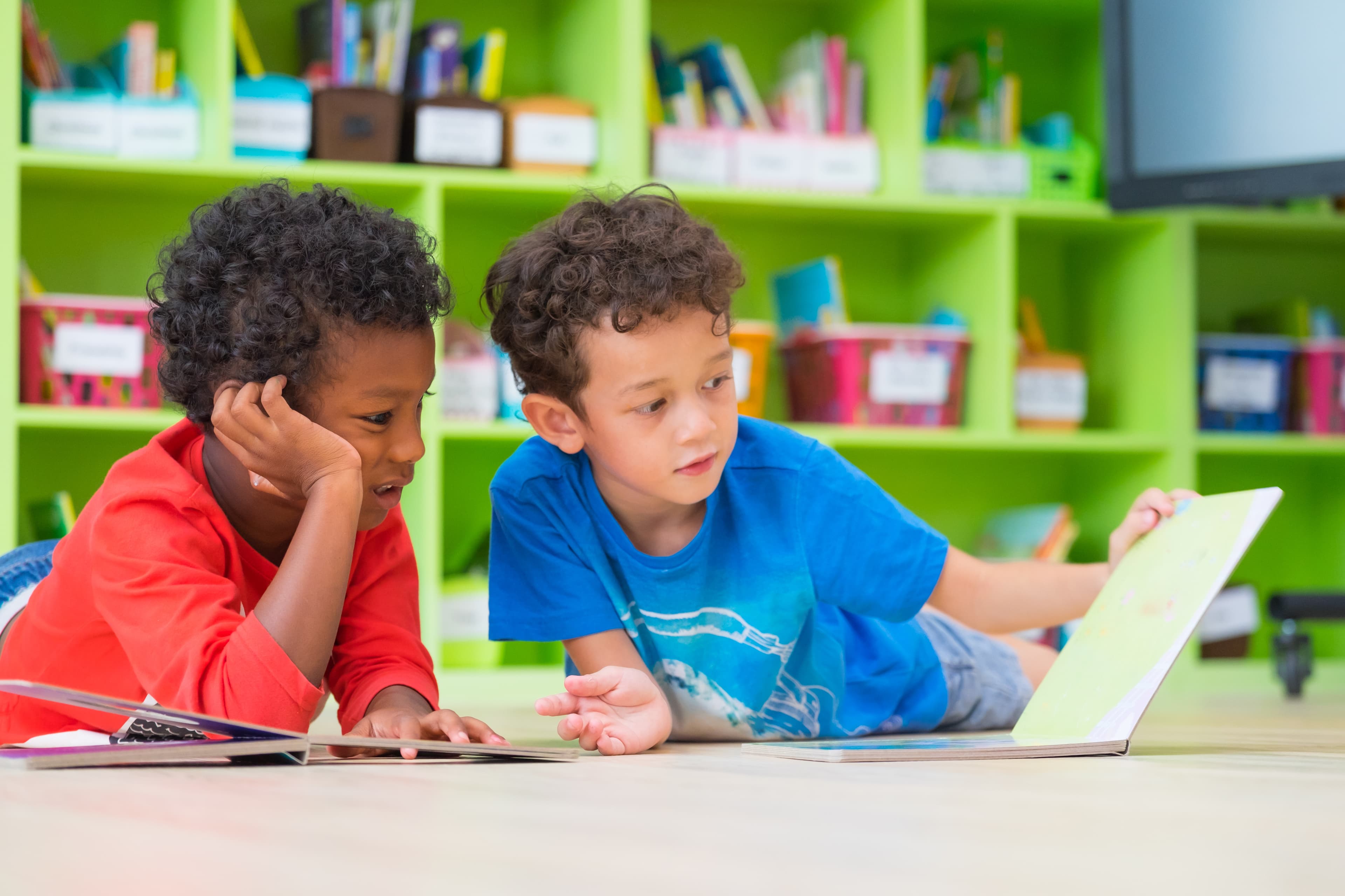 A smiling child in a classroom writing in a notebook