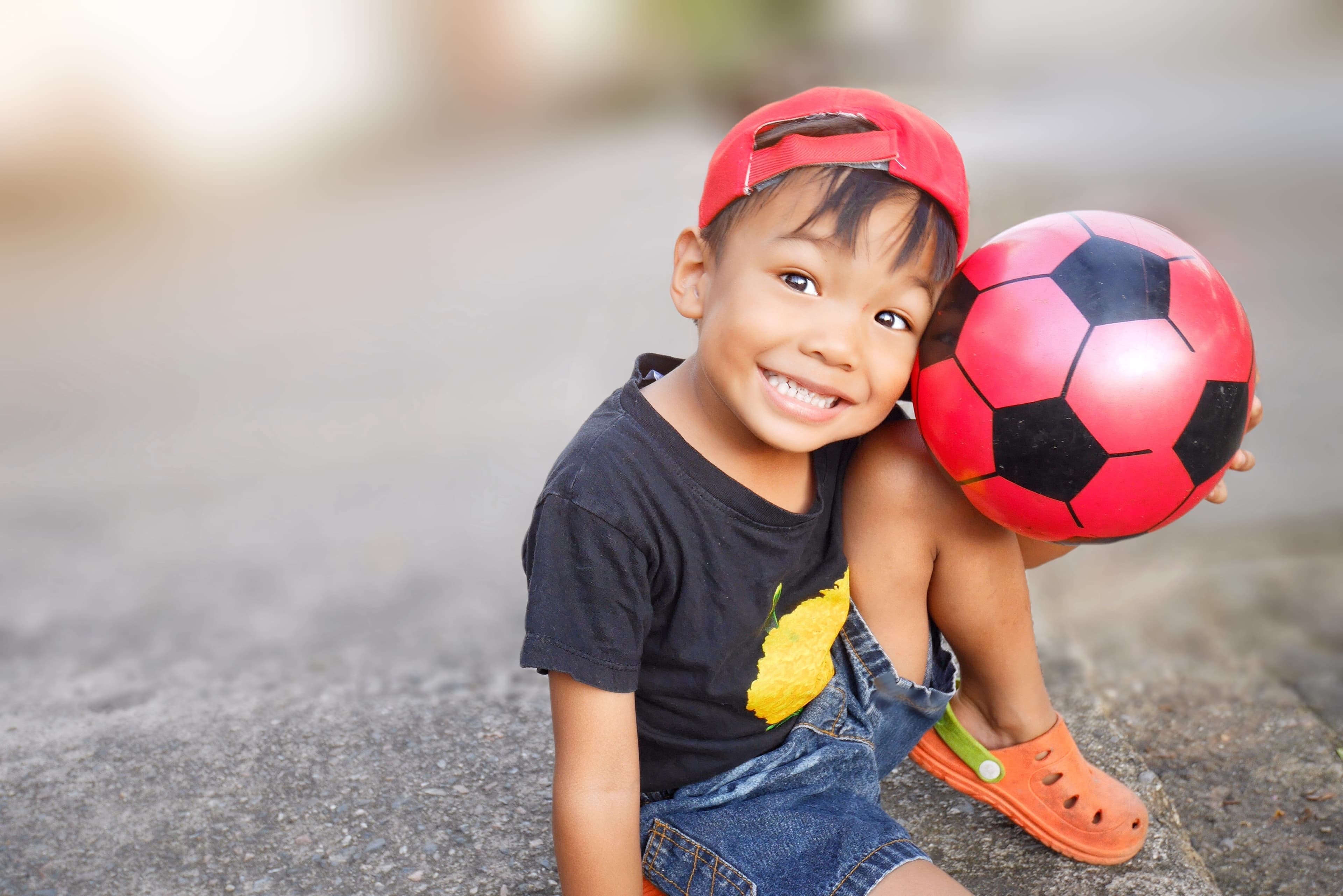 A smiling child holding a soccer ball