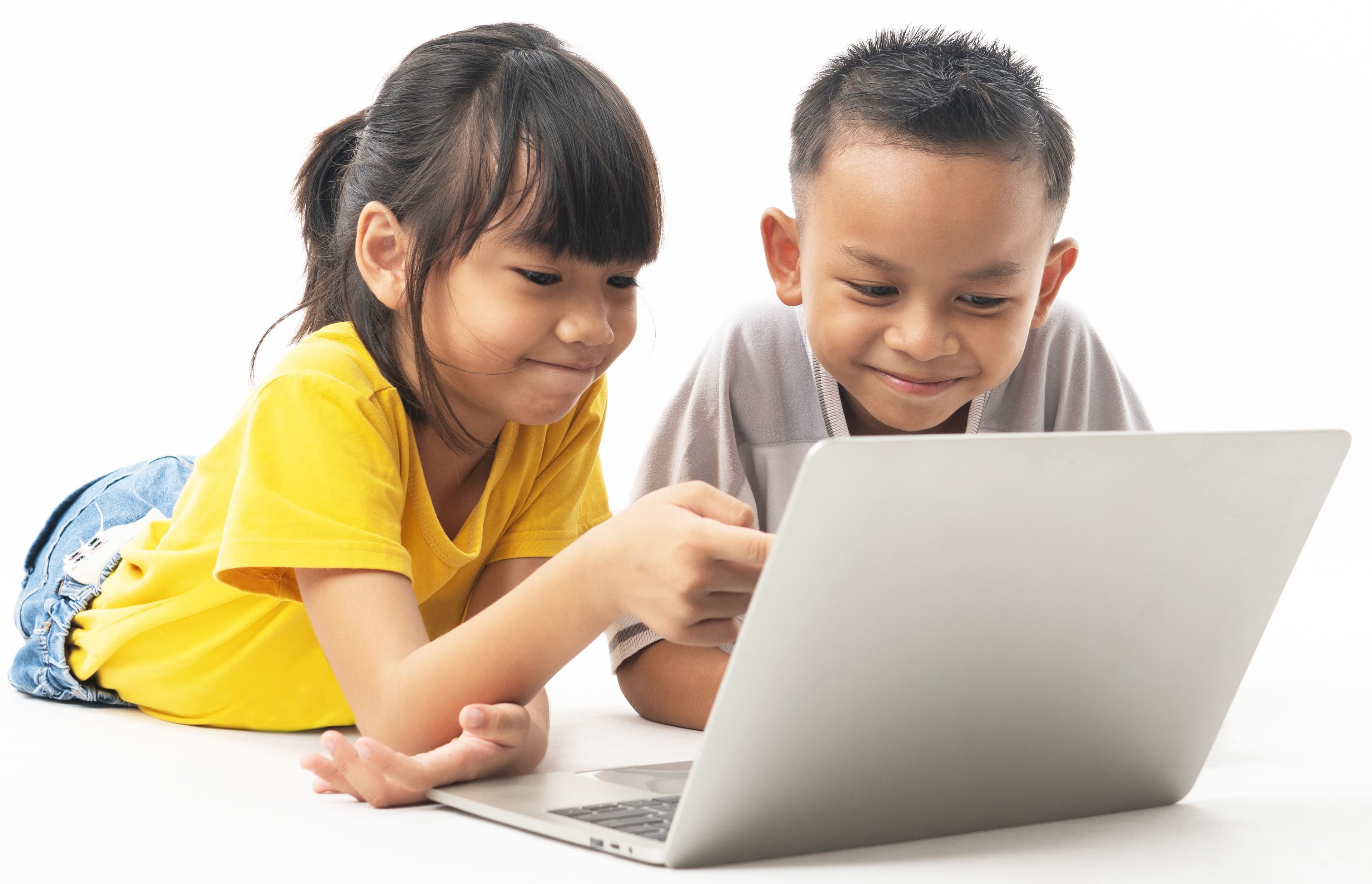 Two children smiling and working on a laptop