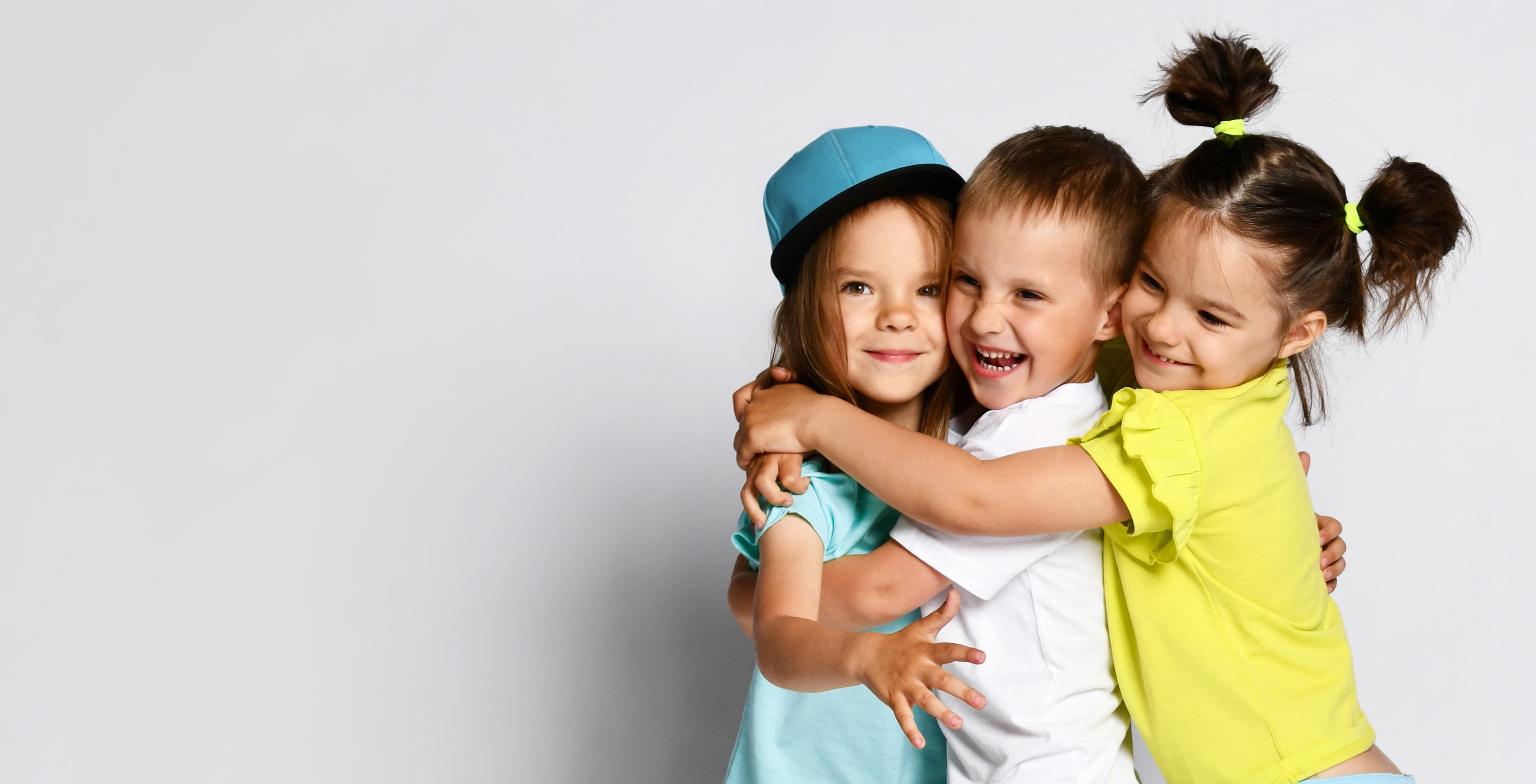 Three children smiling and hugging each other