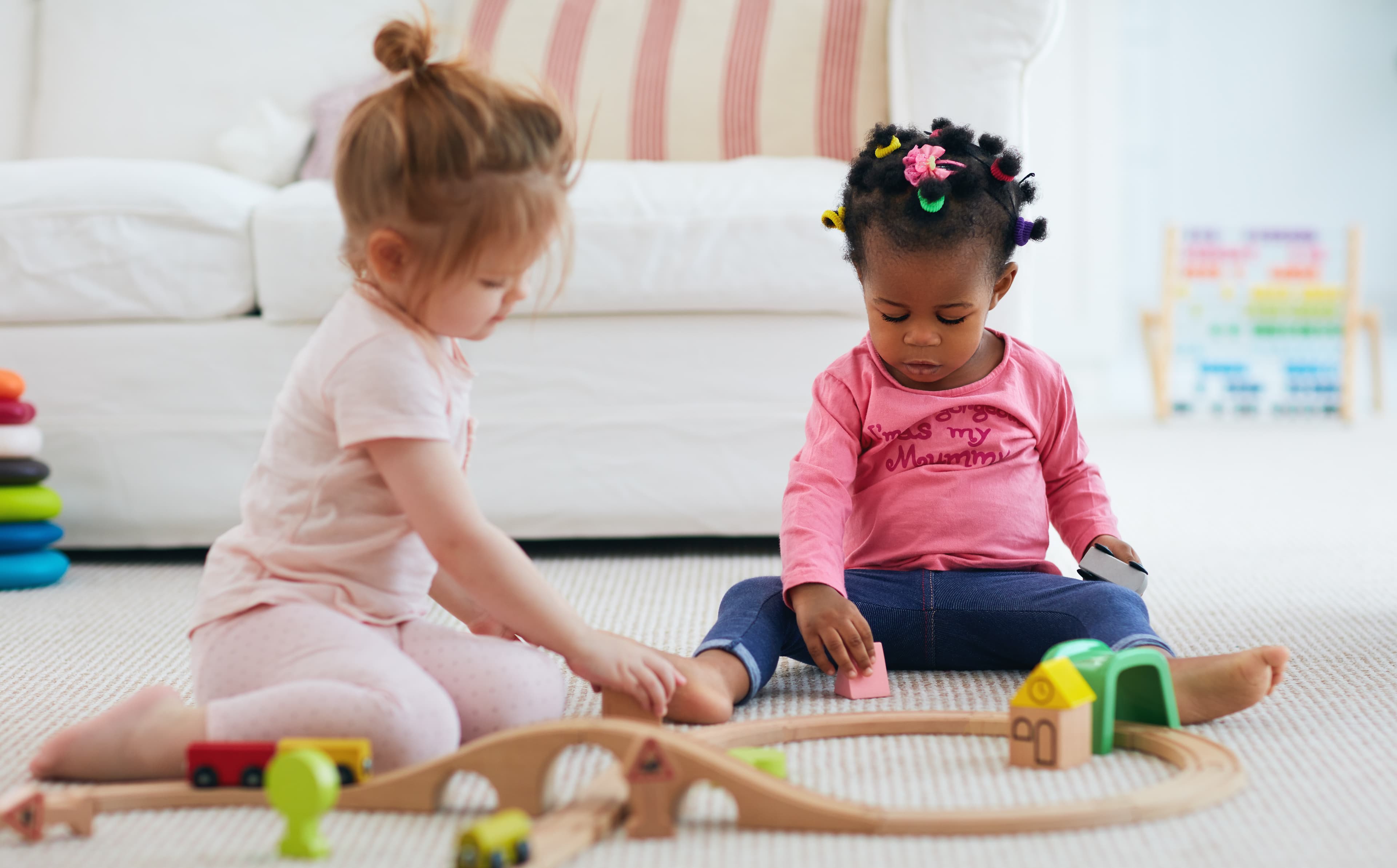 Two toddlers playing with a toy train set.