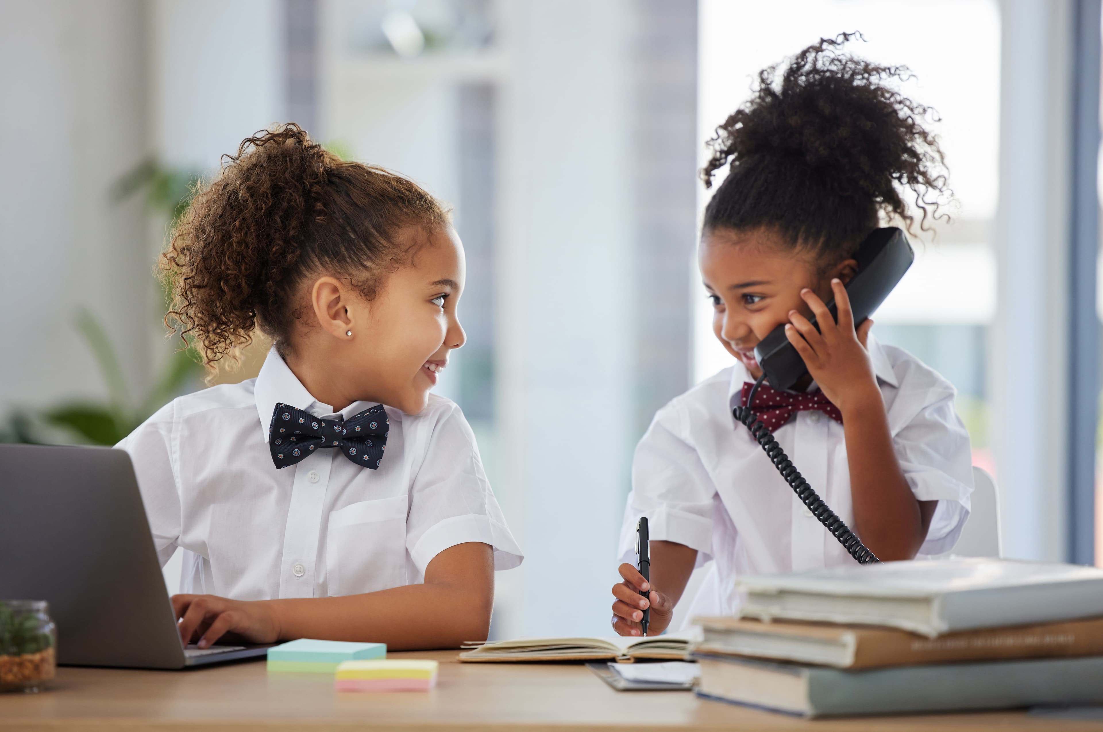 Two young kids in business attire pretending to be at work at an office