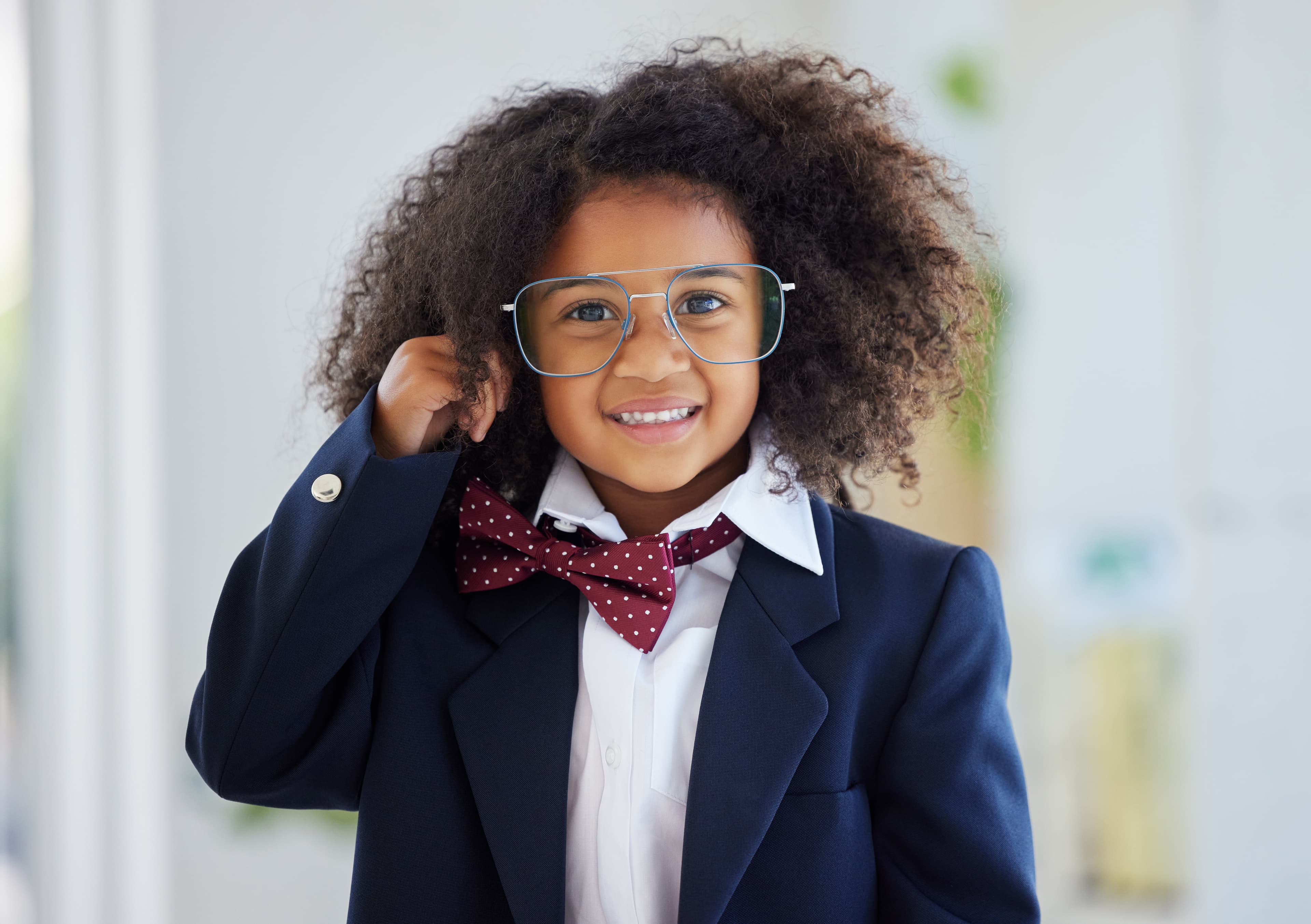A child wearing a jacket and bowtie smiling at the camera