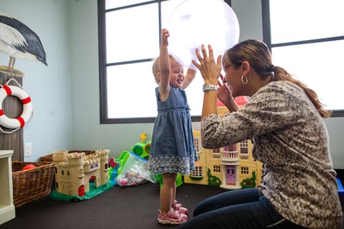 A woman and toddler smiling and playing with a bouncy ball