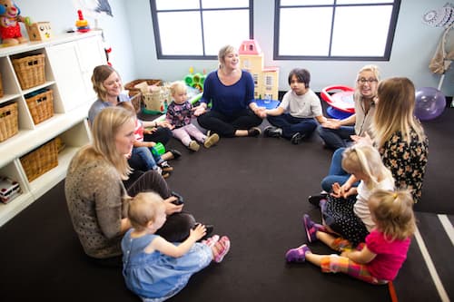 A group of teachers and children holding hands and sitting in a circle