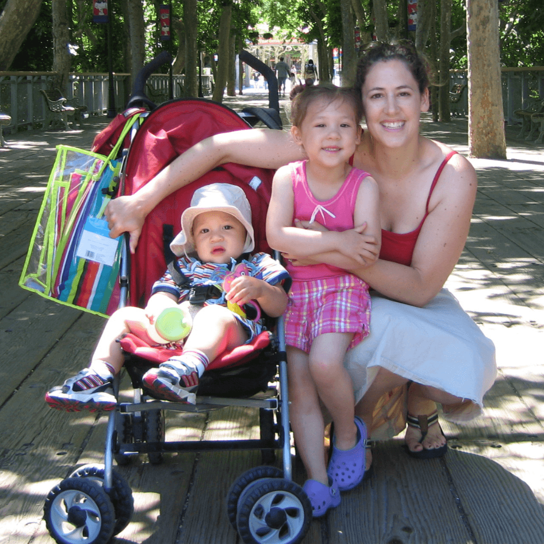 First Steps for Kids Director of Operations Karyn Lew kneeling with two children