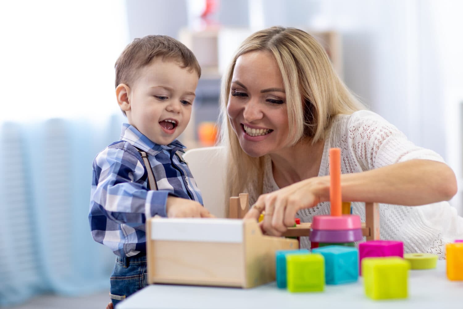 A toddler and adult playing with blocks on a table