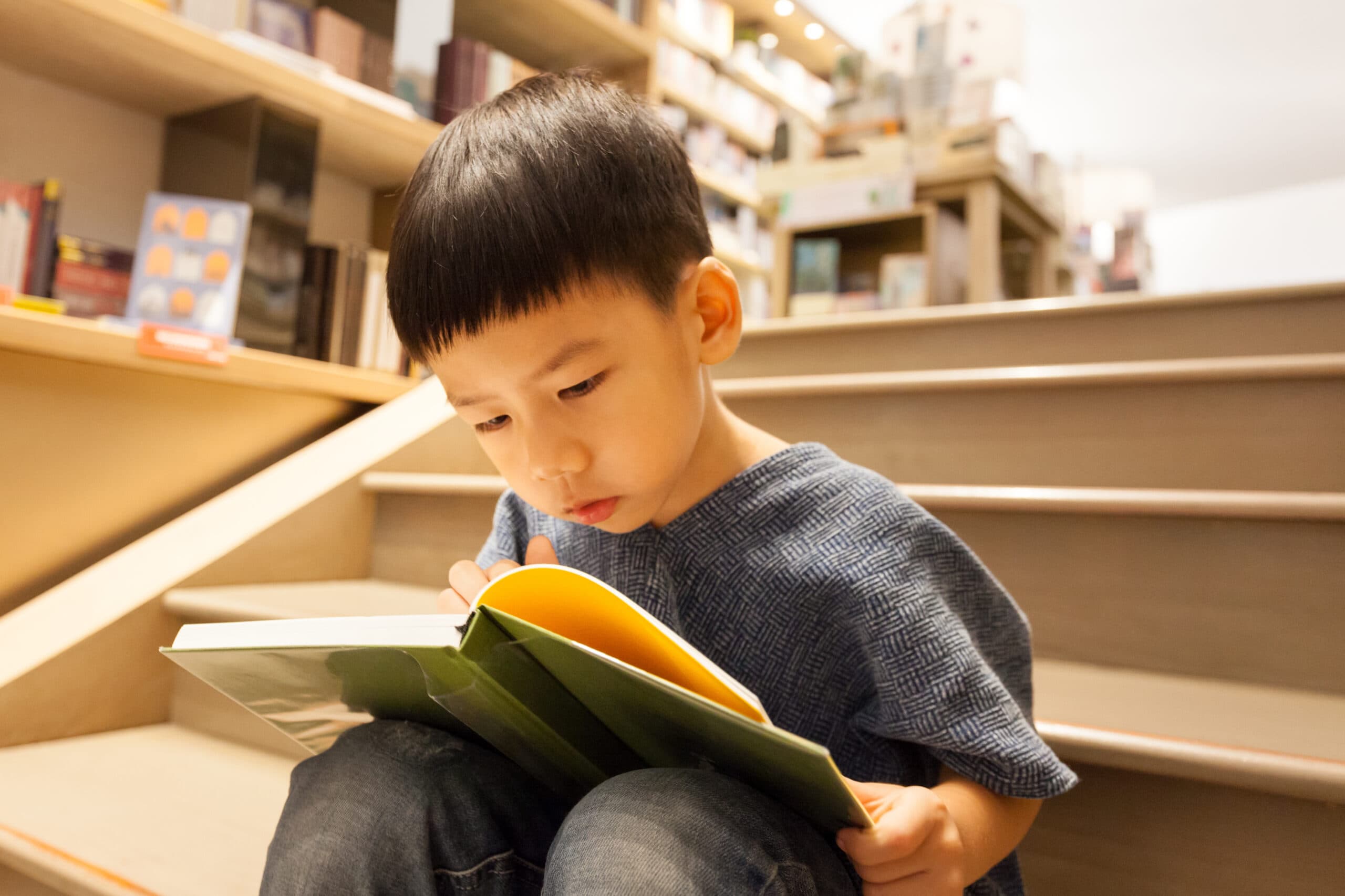 Young boy reading while sitting on stairs