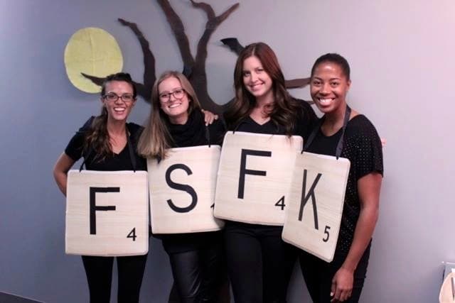Four women holding up very large scrabble peices 