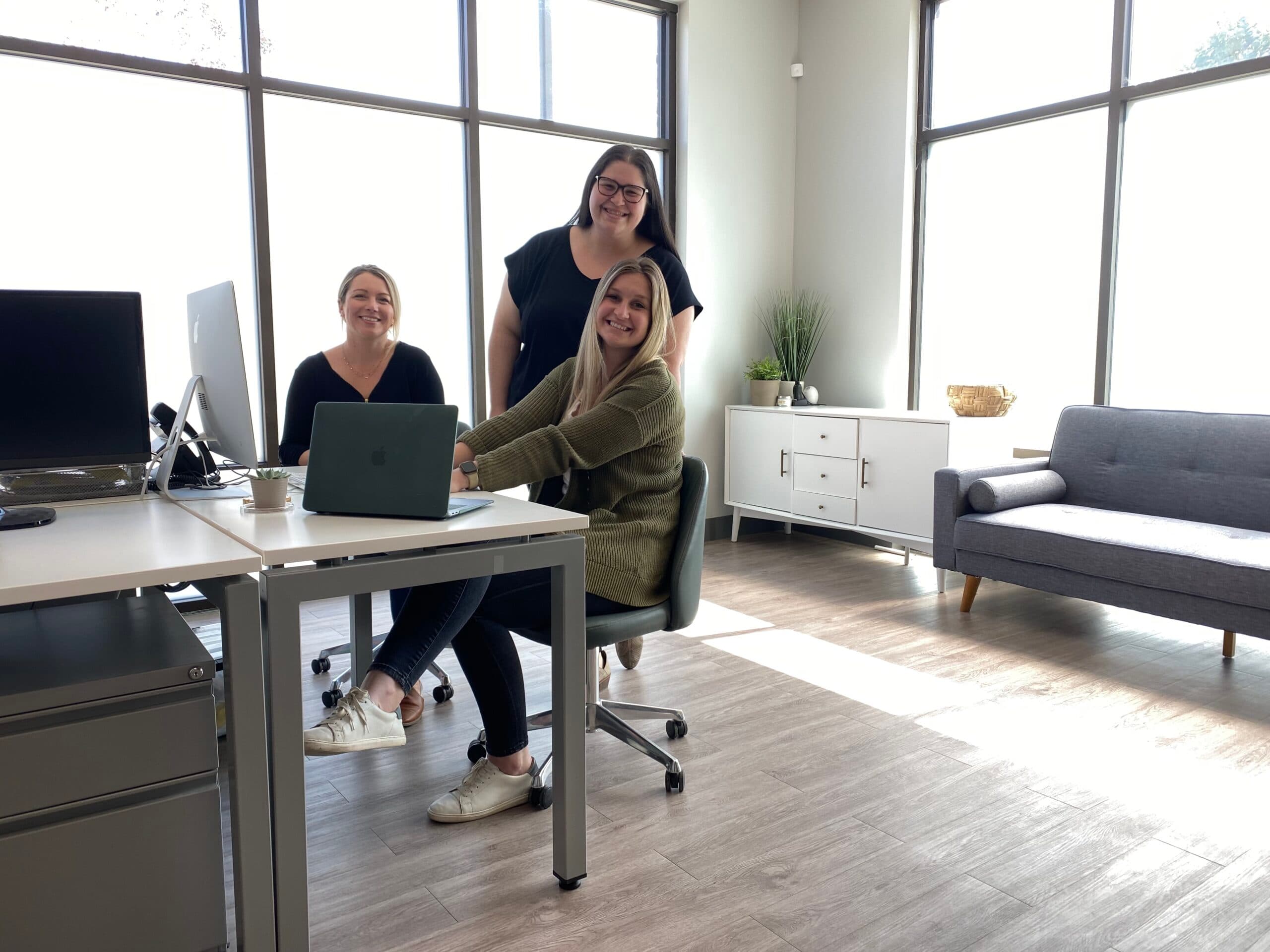 First step staff gathered around a desk, smiling.
