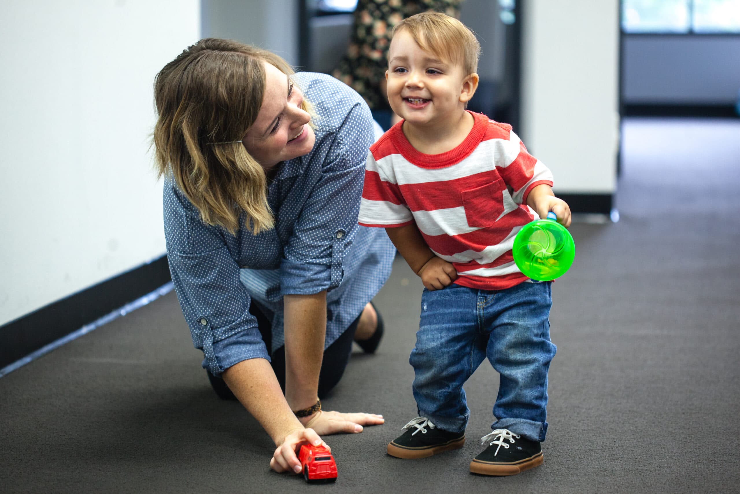 Women and young boy playing with kids toys, smiling.