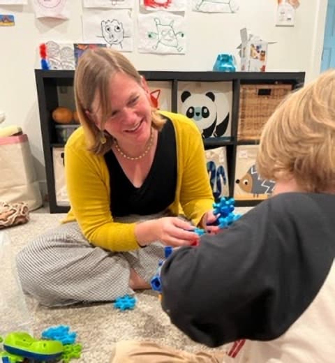Lauren Taylor sitting on the floor with young student